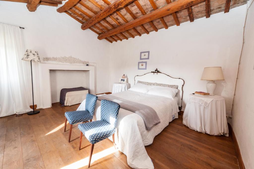 a white bedroom with a bed and two chairs at Le Bumbarelle in Tavoleto