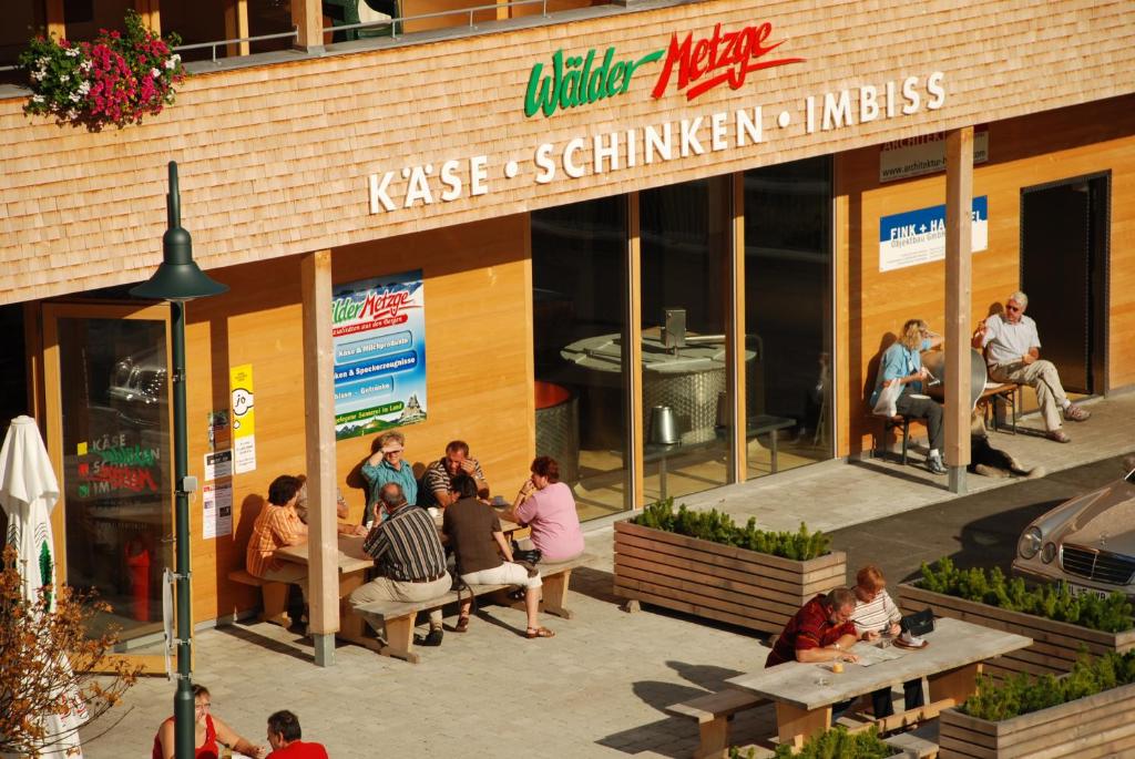 eine Gruppe von Personen, die vor einem Restaurant sitzen in der Unterkunft Wäldermetzge Hüttenzimmer und Wohnungen in Warth am Arlberg