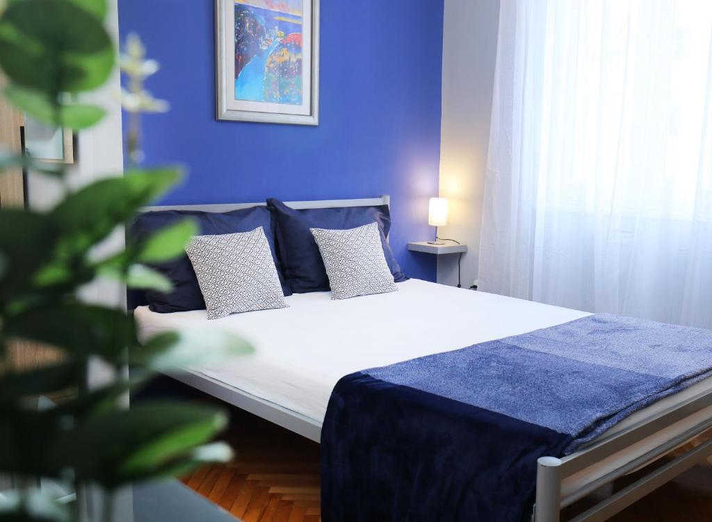 ein blaues Schlafzimmer mit einem Bett mit blauer Bettwäsche und Kissen in der Unterkunft SPLIT CHIC Studio in Split