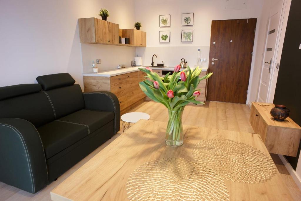 uma sala de estar com um vaso de flores sobre uma mesa em Apartament na Piernikowym z miejscem postojowym em Toruń