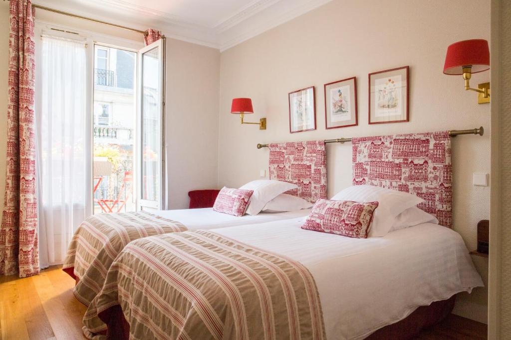 two beds in a hotel room with a window at New Orient Hotel in Paris