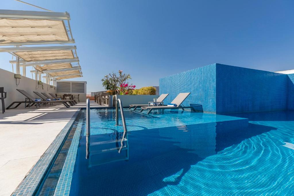 瓦哈卡市帕拉多阿尔卡拉酒店的一座建筑物边的蓝色瓷砖游泳池