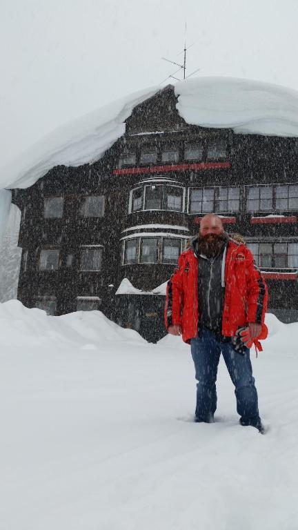 a man standing in the snow in front of a building at Berghotel Almagmach in Immenstadt im Allgäu