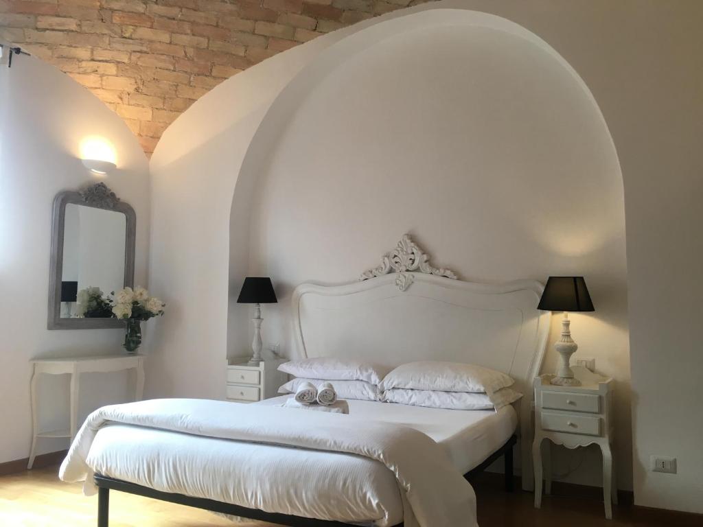 ein Schlafzimmer mit einem weißen Bett und einer Ziegelwand in der Unterkunft La finestra sul Colosseo B&B 1 in Rom