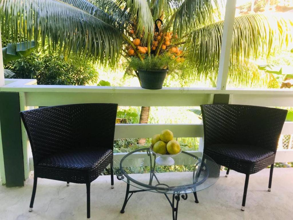2 Stühle und ein Tisch mit einer Obstschale darauf in der Unterkunft Bougainvillea Apartments 2 in Castries