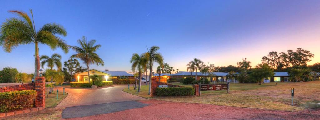 ein Haus mit Palmen und einer Auffahrt in der Unterkunft Heritage Lodge Motel in Charters Towers