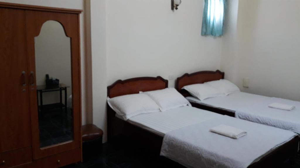 a bedroom with two beds and a cabinet and a mirror at Khách sạn Duy Hoàng in Buon Ma Thuot