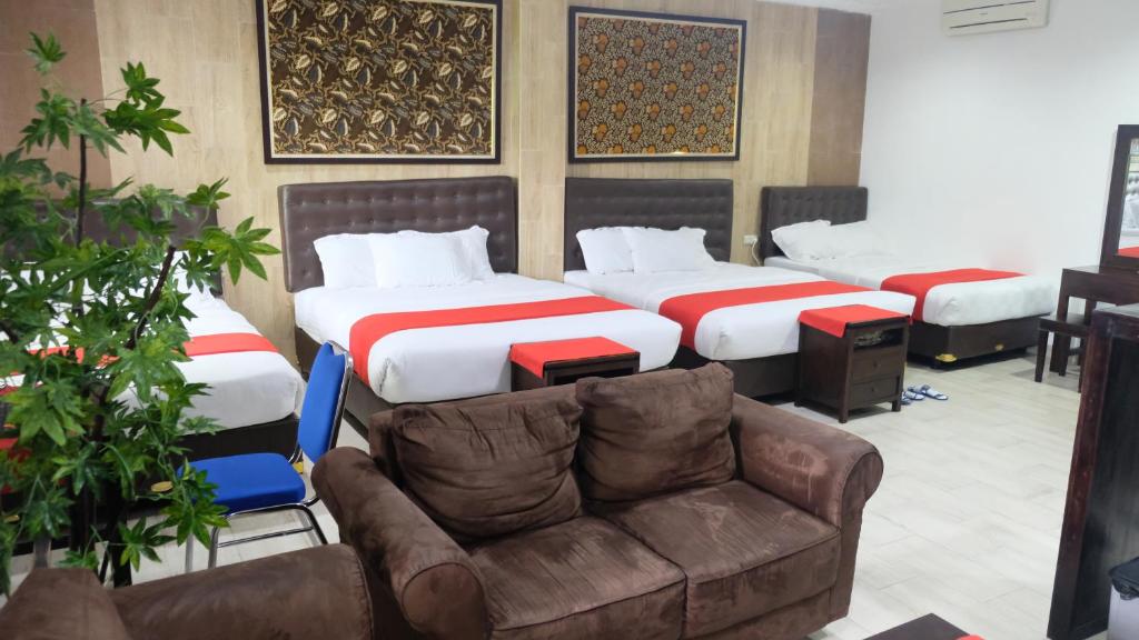 a hotel room with two beds and a couch at BeOne House Jogja in Yogyakarta