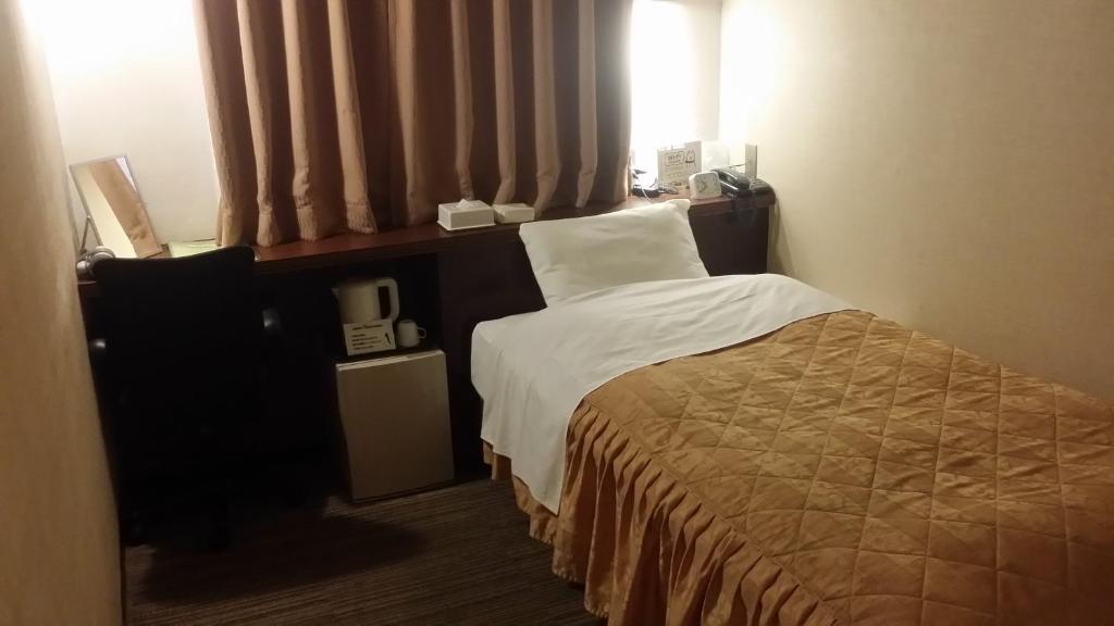 a hotel room with a bed and a window at Hotel Onahama Hills in Iwaki