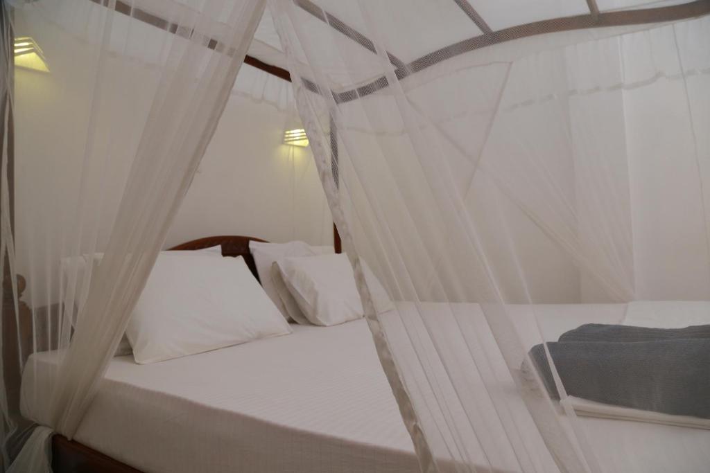 ein Schlafzimmer mit einem weißen Bett mit Baldachin in der Unterkunft THE KING APARTMENT in Hikkaduwa