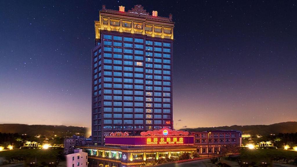 Un grand bâtiment avec des lumières allumées la nuit dans l'établissement Nanyang King's Gate Hotel, à Canton