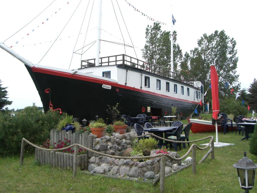 um barco sentado na relva ao lado de uma mesa em Hotelschiff Stinne em Wustrow
