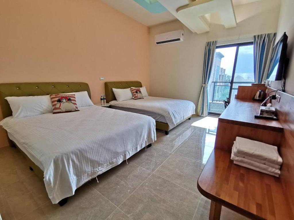 台東市的住宿－愛町堡民宿，一间卧室设有两张床、一张桌子和一个窗口。