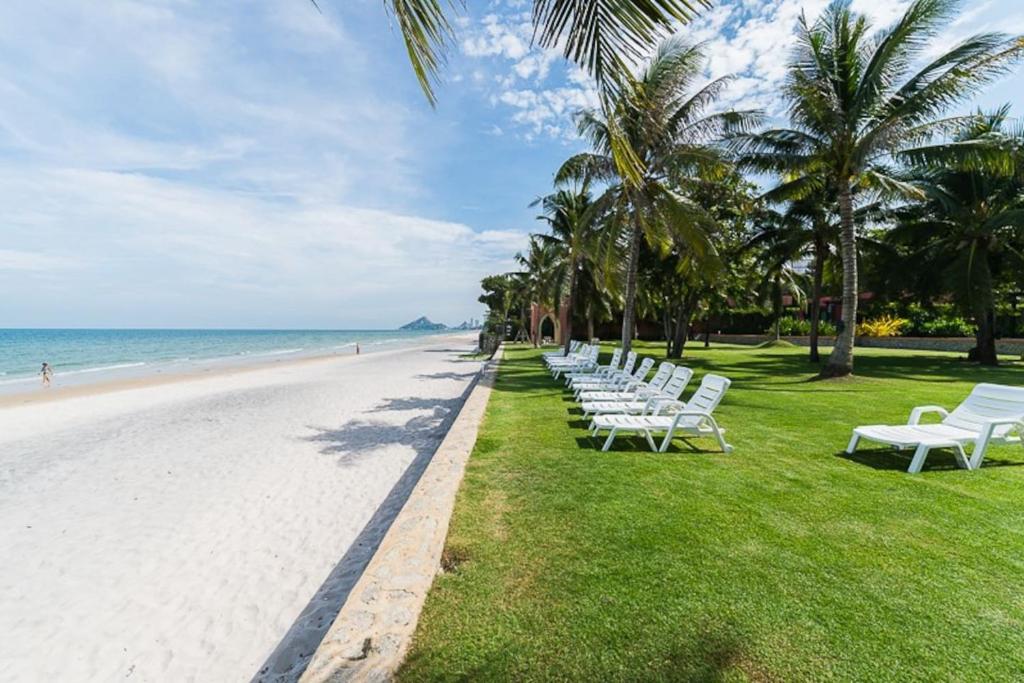 a row of white benches sitting on the beach at Marrakesh huahin 4bedrooms with seaview 248 in Hua Hin