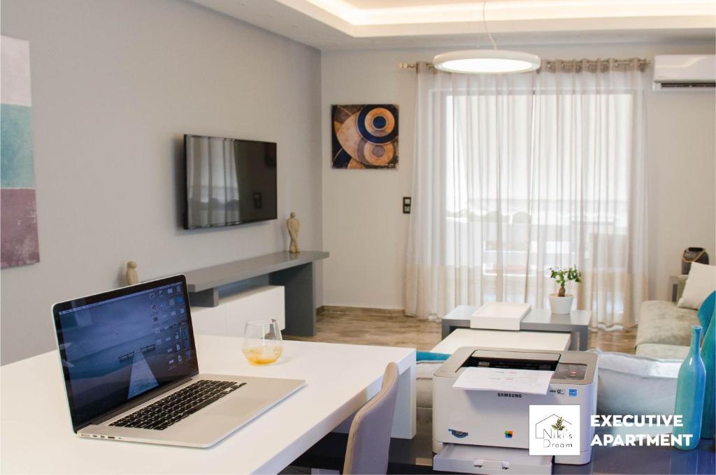 a living room with a laptop on a white table at Nikis Dream Luxury Apartments in Chania