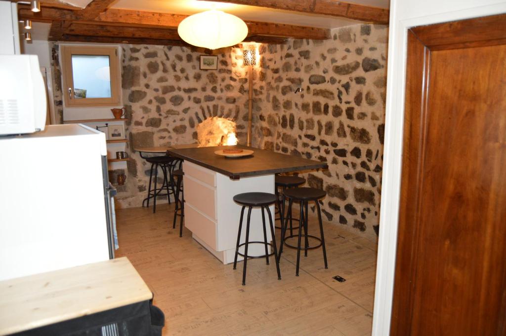 - une cuisine avec une île dans une chambre dotée de murs en pierre dans l'établissement Le gîte du Bessat, au Puy-en-Velay