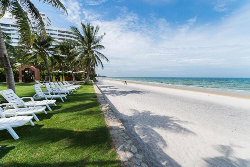 a row of white lounge chairs on the beach at Marrakesh Huahin 1bedroom with seaview 148 in Hua Hin