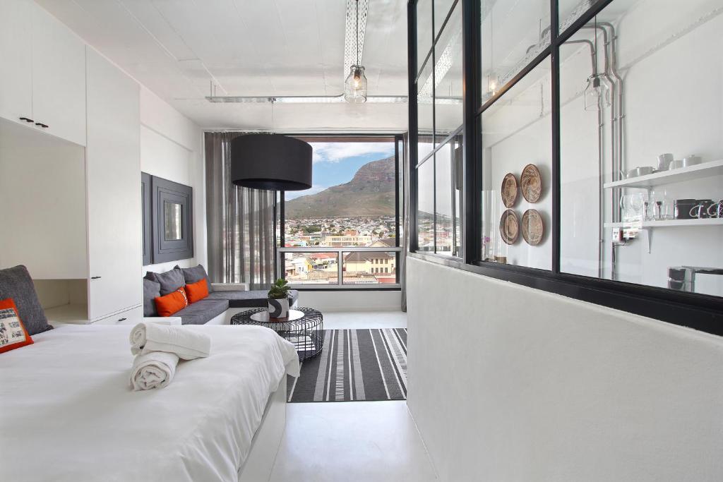 um quarto branco com uma cama e uma grande janela em Harbour View Apartments em Cidade do Cabo