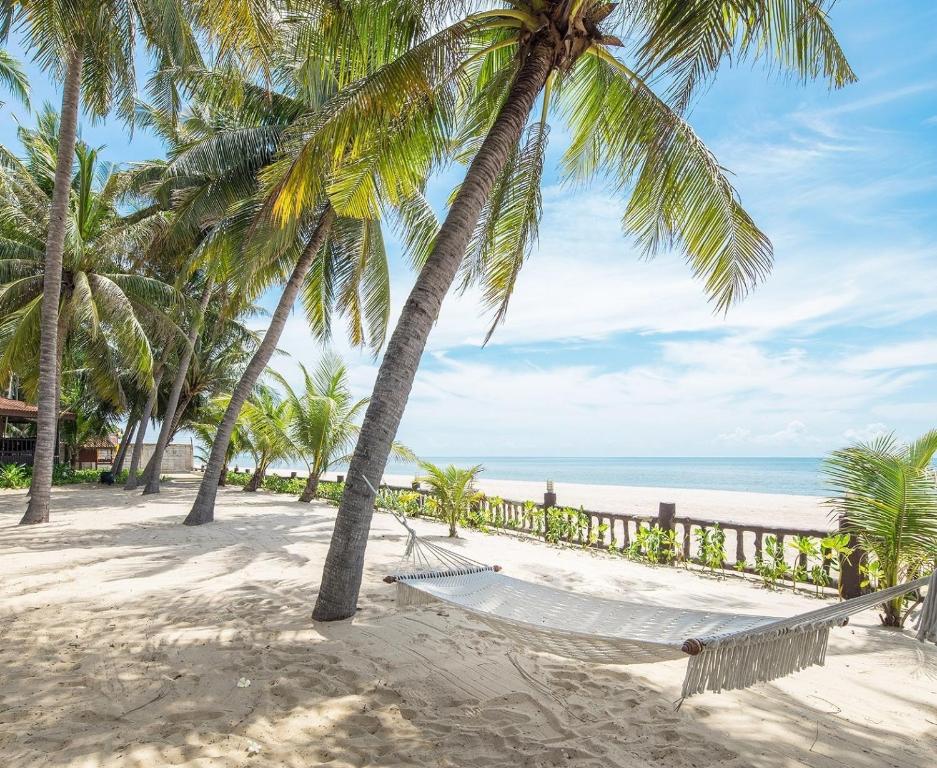 a hammock on a beach with palm trees and the ocean at Regent - Chalet, Hua Hin in Cha Am