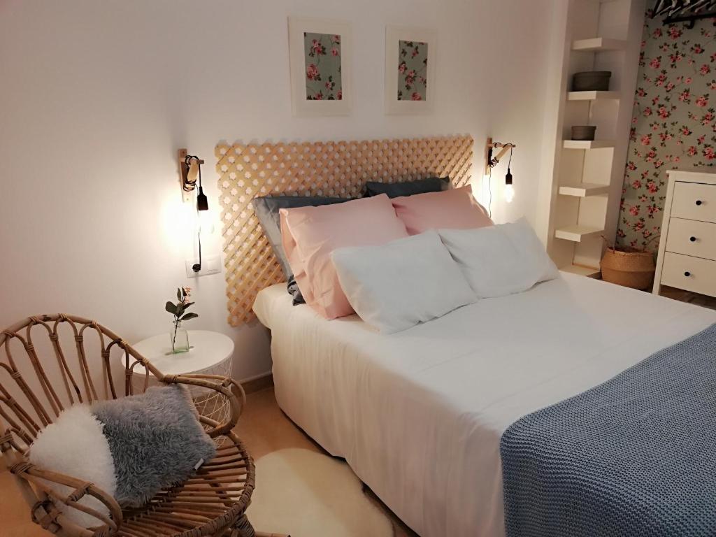 um quarto com uma cama com almofadas cor-de-rosa e uma cadeira em Paraíso en la Loma de Santa Pola em Gran Alacant