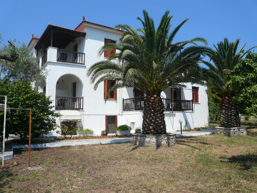 a house with two palm trees in front of it at Liossis Rooms & Apartments in Skopelos Town