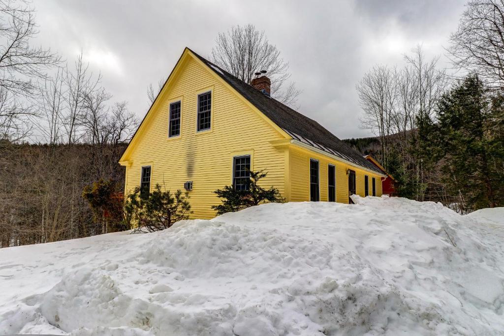 una casa gialla con un mucchio di neve davanti di Mt. Ellen's Backyard Bungalow a Moretown