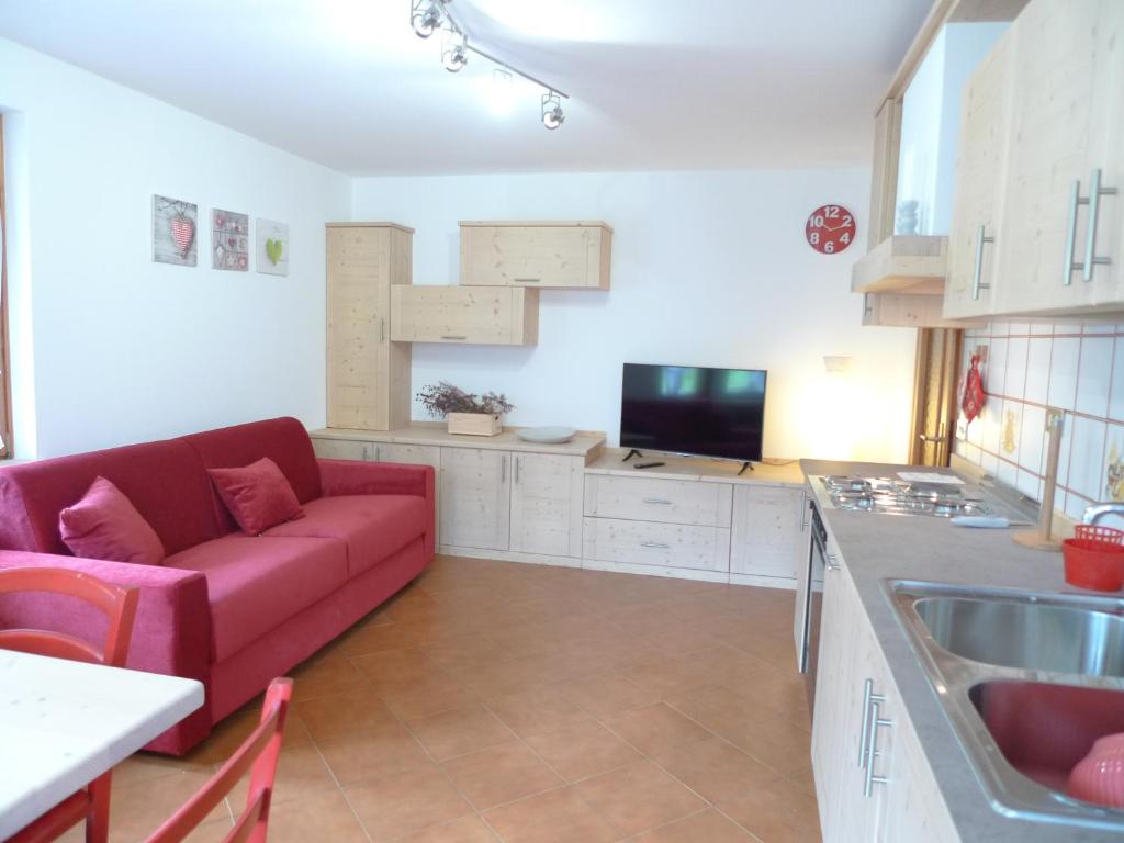 salon z czerwoną kanapą w kuchni w obiekcie Casa Sorarù w mieście Rocca Pietore