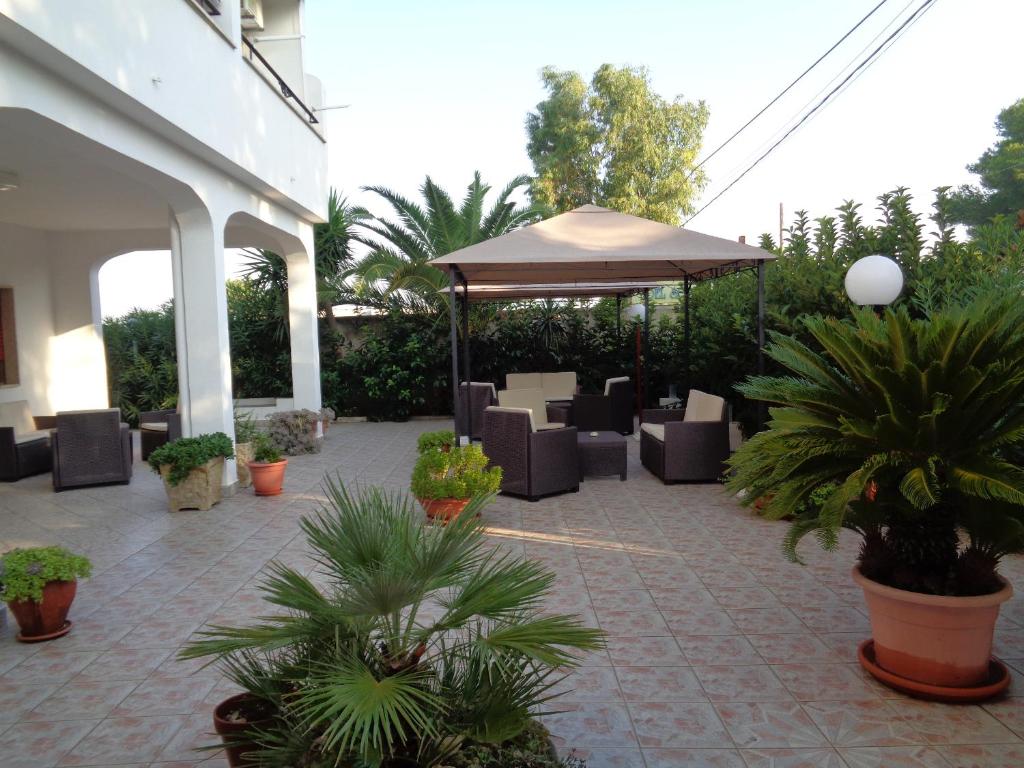 a patio with chairs and an umbrella and plants at Hotel Villa del Sole in Porto Cesareo