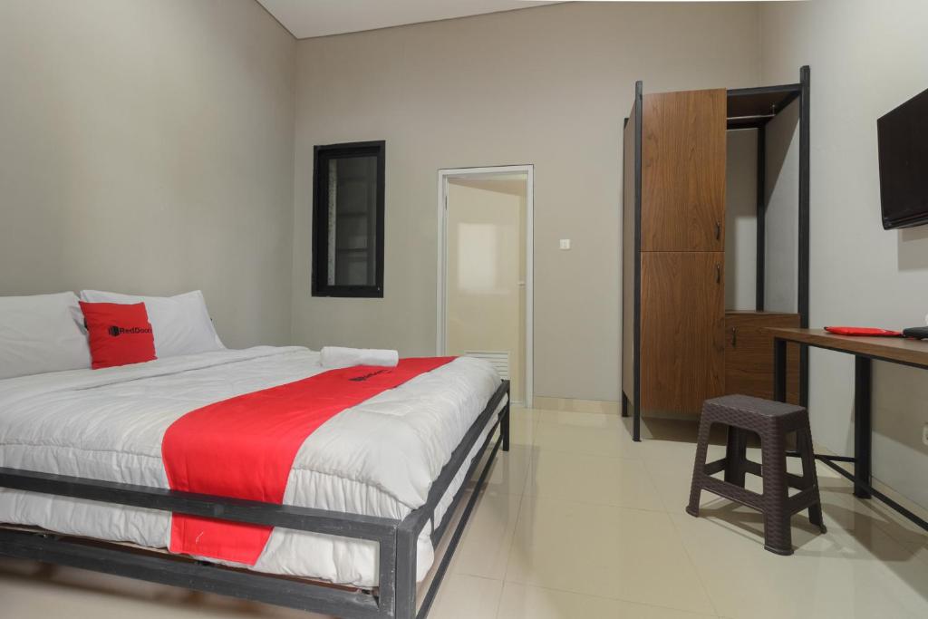1 dormitorio con 1 cama con manta roja en RedDoorz near Puri Indah Mall, en Yakarta