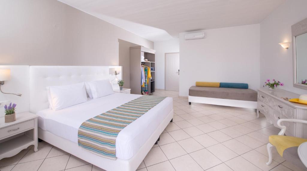 a white bedroom with a bed and a couch at Dore Boutique Hotel in Agia Marina Nea Kydonias