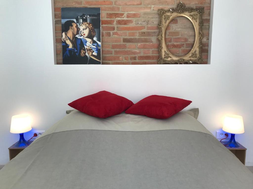 a bedroom with a bed with two red pillows and a mirror at La bulle de Gaston in Toulouse