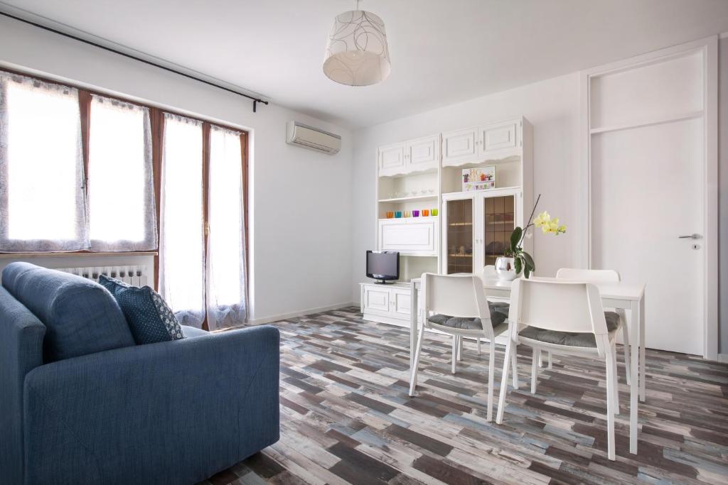 uma sala de estar com um sofá azul e uma mesa e cadeiras em Casa Girasole em Bardolino