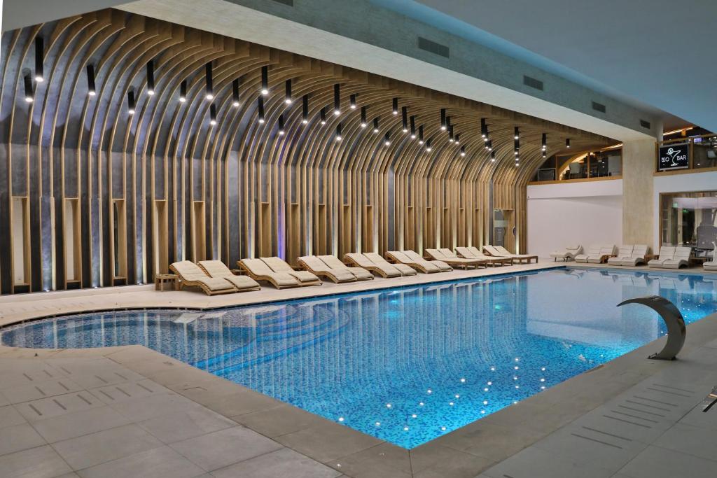a large swimming pool with lounge chairs in a building at Forest Retreat&Spa in Oveselu