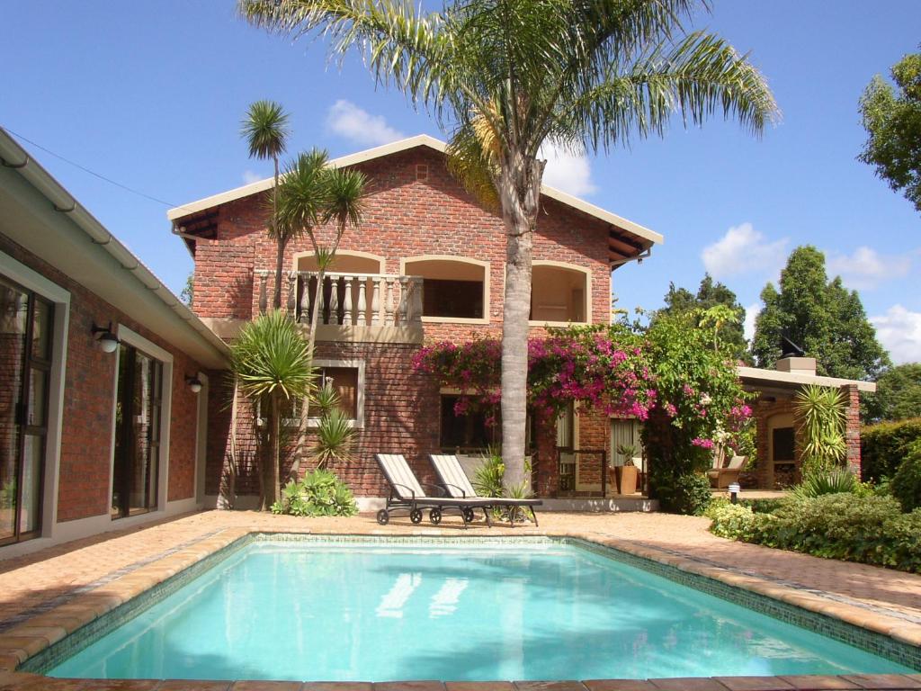 a house with a swimming pool in front of a house at Aziza Guest House in George