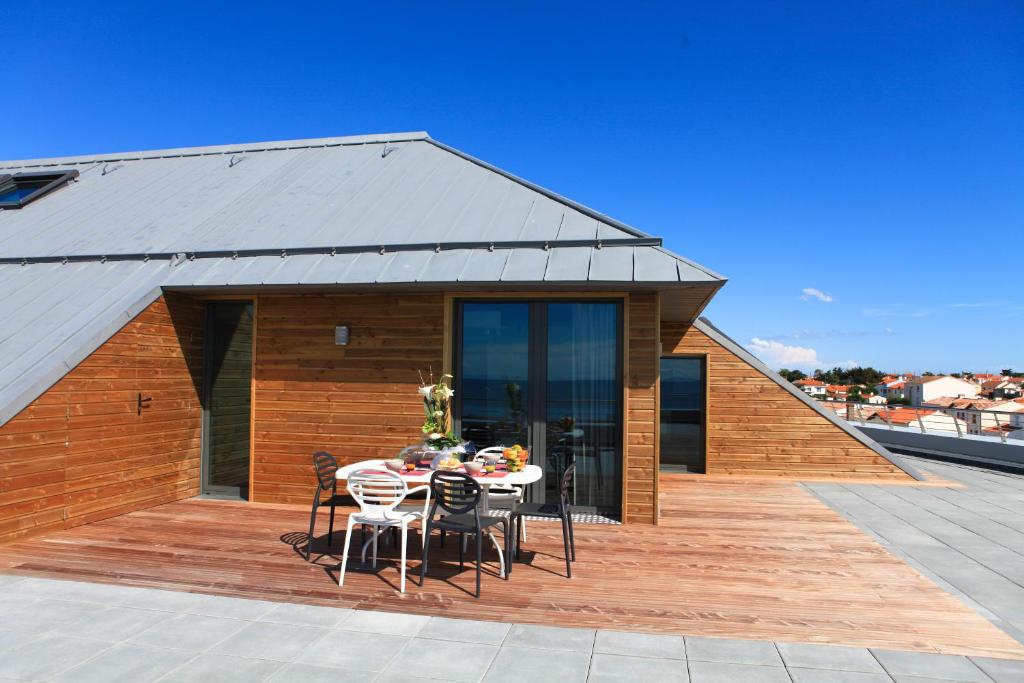 a house with a wooden deck with a table and chairs at Les Terrasses de l'Océan in Saint-Hilaire-de-Riez