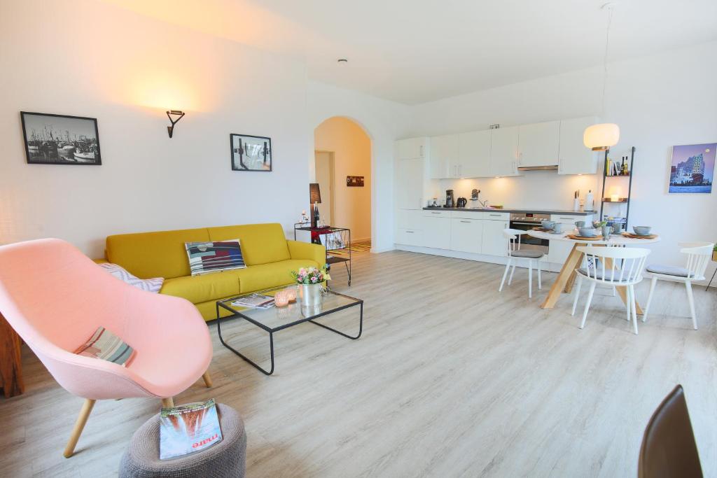 a living room with a yellow couch and a kitchen at Appartements Villa Schwanenteich in Fehmarn