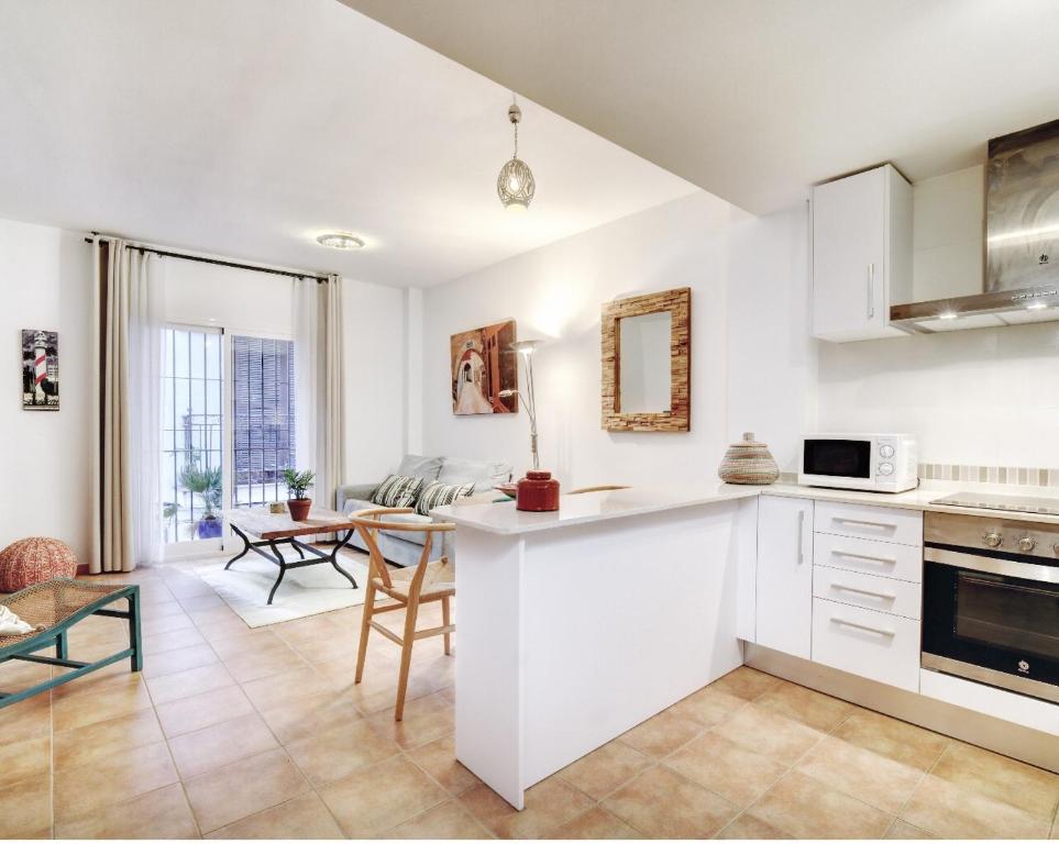 a kitchen and living room with white cabinets and a table at Old Town Apartment near the beach in Marbella