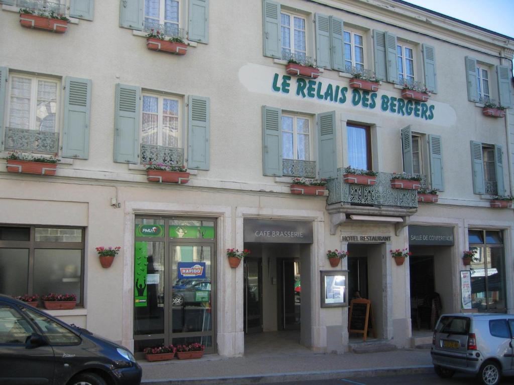 a building on a street with cars parked in front of it at Le Relais des Bergers in Saint-Martin-en-Haut
