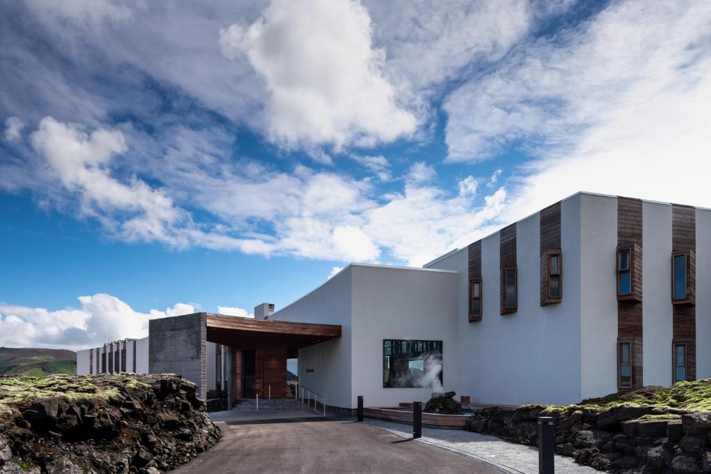 a white building on a hill with a cloudy sky at The Retreat at Blue Lagoon Iceland in Grindavík