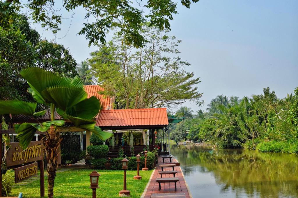 un edificio junto a un río con árboles en บ้านกรนรา Baan Kornnara, en Amphawa