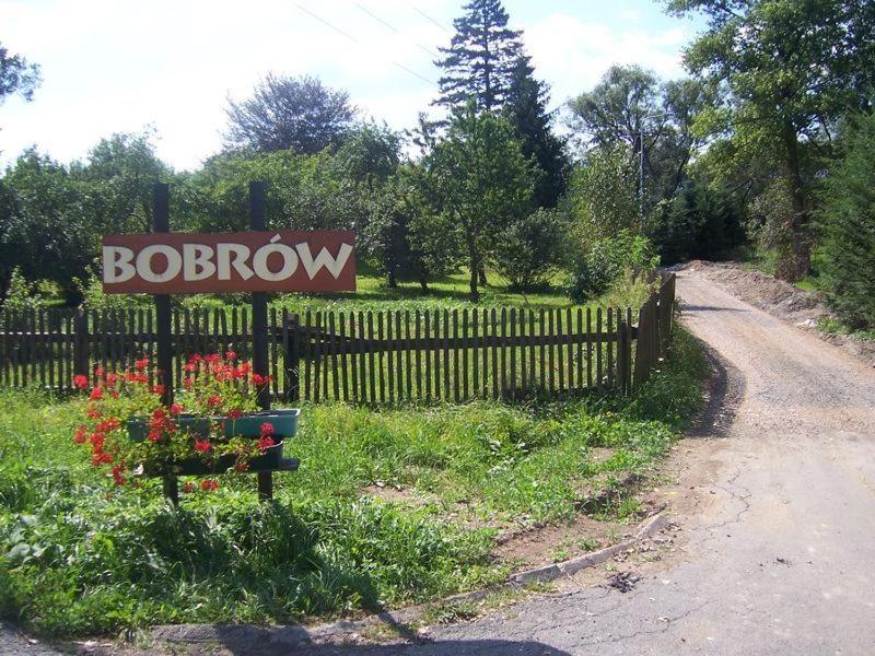 a wooden fence with a bouquet of flowers next to a sign at Karpnicka Struga W Dolinie Pałaców i Ogrodów in Jelenia Góra