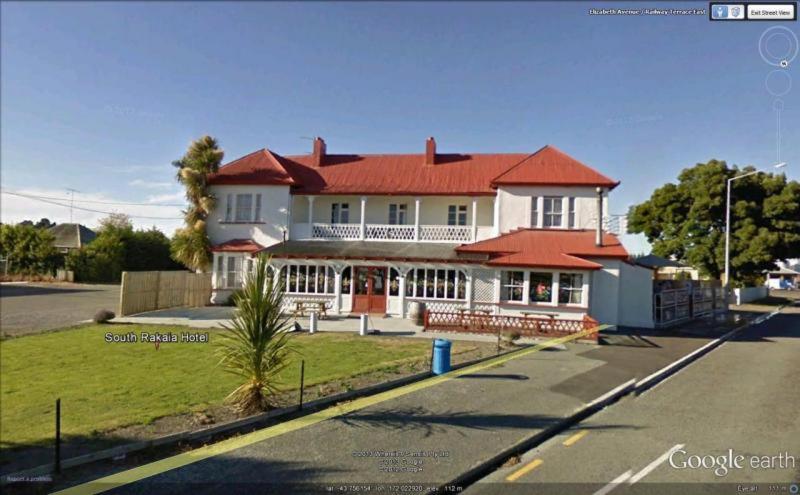 a large white house with a red roof on a street at South Rakaia Hotel in South Rakaia