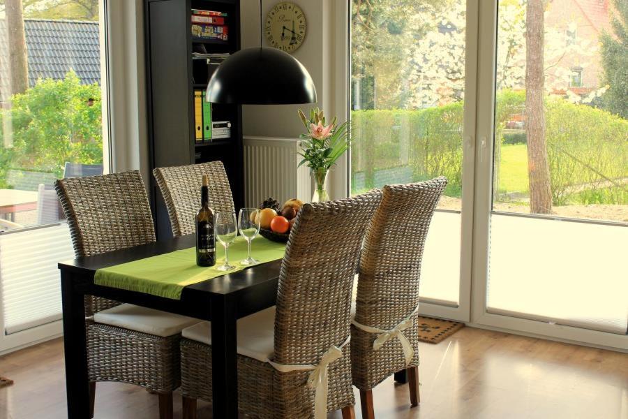 een eettafel met stoelen en een fles wijn bij K 104 EG - moderne Ferienwohnung am See mit Sauna & Kamin in Marienfelde