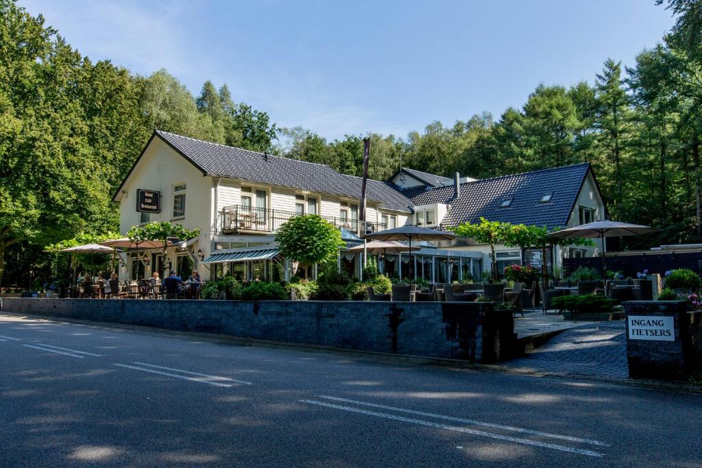 een huis met tafels en parasols aan de straatkant bij Hotel Buitenlust in Hoenderloo