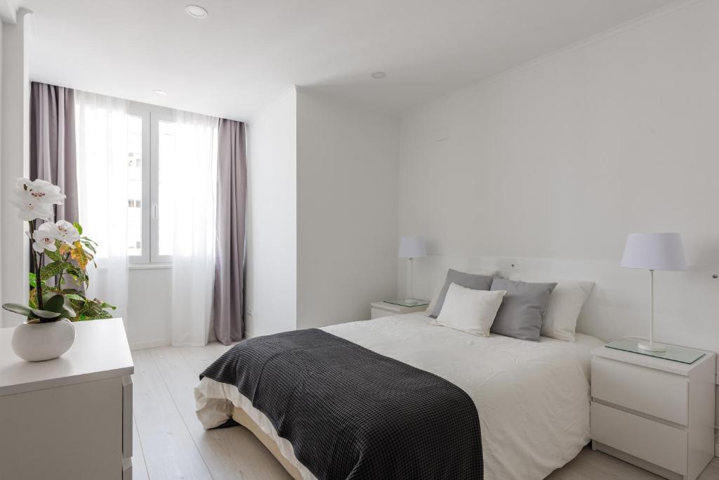 a white bedroom with a bed and a window at Light-Filled, Fully Renovated Apt near Belém, By TimeCooler in Lisbon