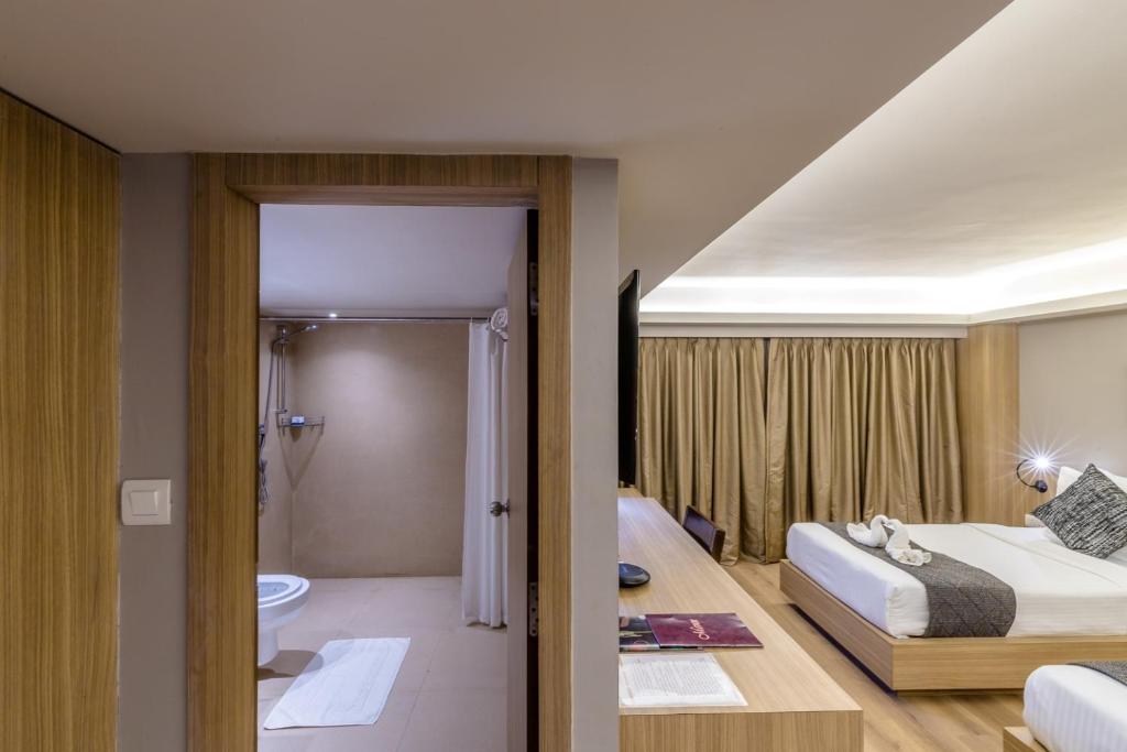 a hotel room with a bed and a bathroom at Princeton Club in Kolkata