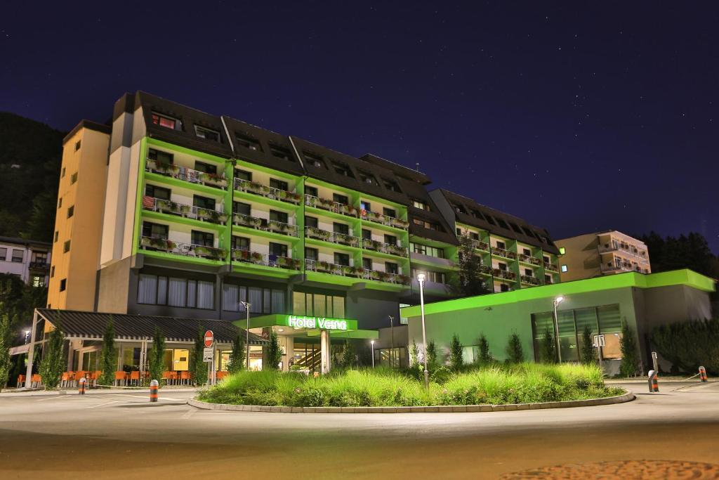 a large building with a green facade at night at Terme Topolsica - Hotel Vesna in Topolšica