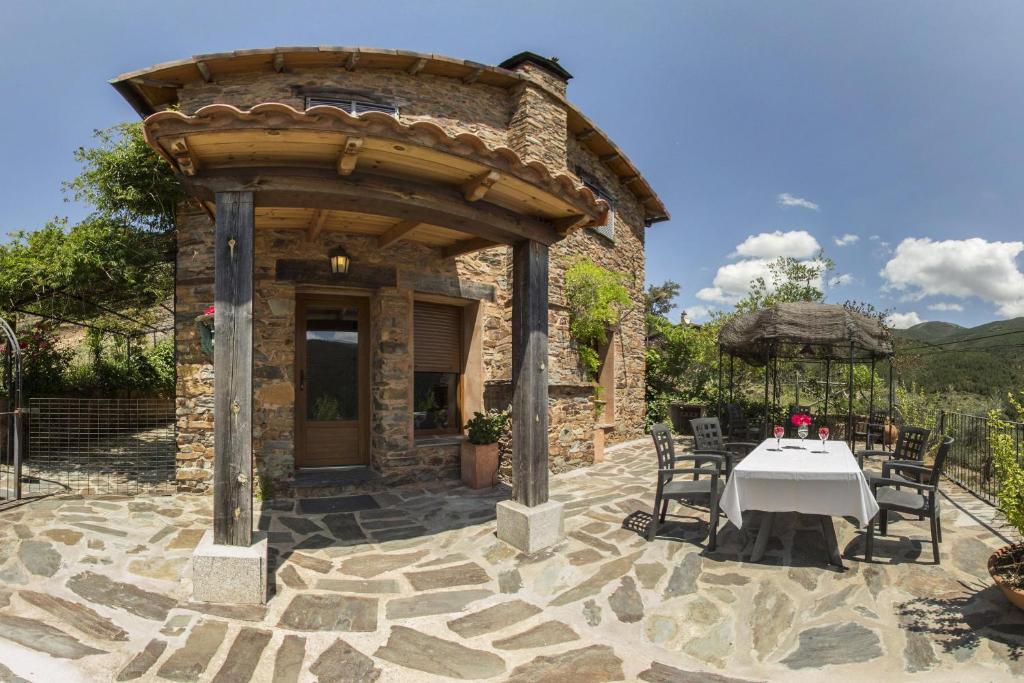 una casa in pietra con tavolo e sedie su un patio di Alqueria De Hurdes a Horcajo