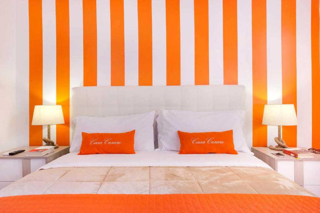 a bed with two orange pillows and two lamps at Casa Cesare in Meta