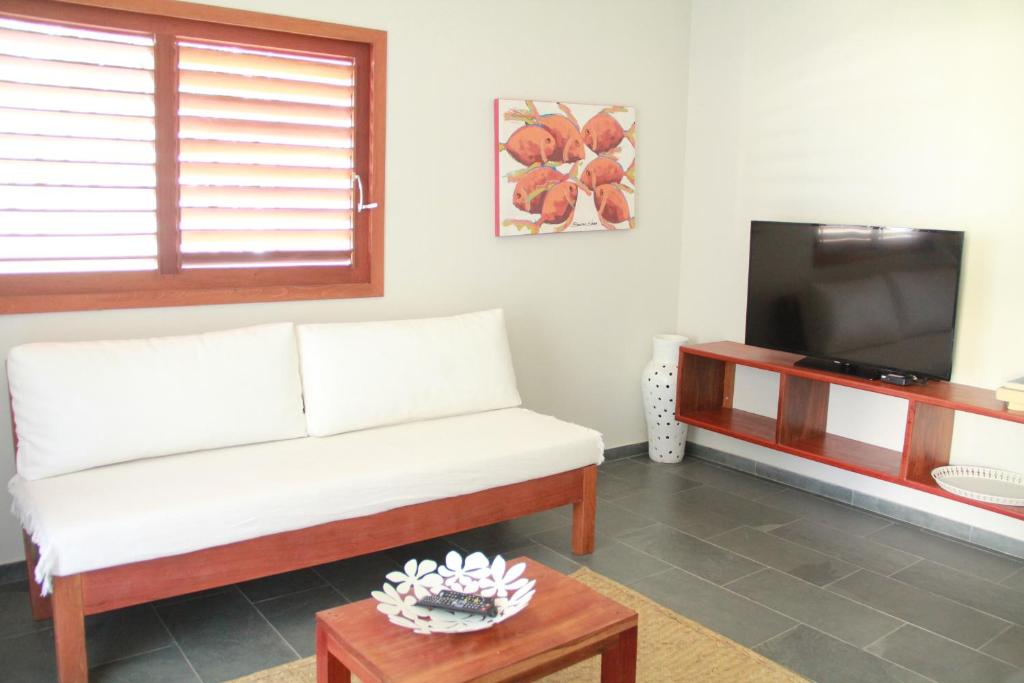 a living room with a white couch and a tv at Flor da Mata in Pipa